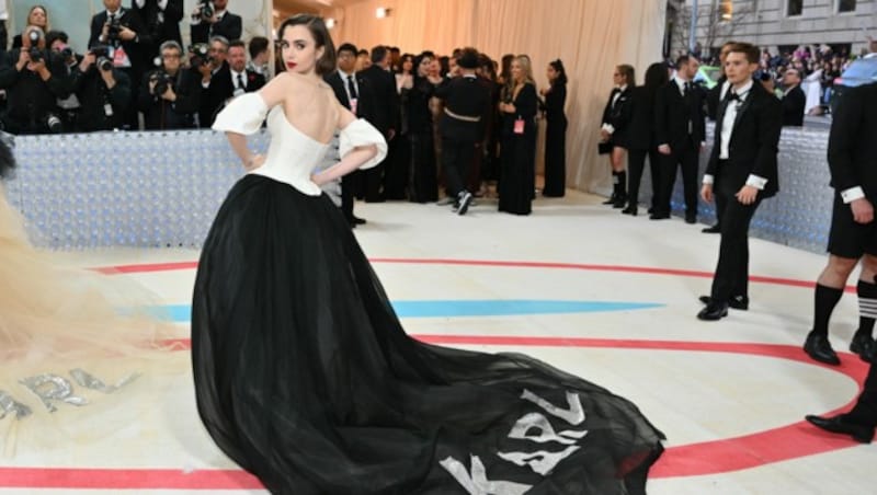 Auf Lily Collins ehrt Karl Lagefeld mit seinem Schriftzug auf der Schleppe. (Bild: APA/Photo by Angela WEISS / AFP)