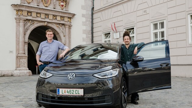 Umweltlandesrat Stefan Kaineder präsentiert seinen vollelektrischen VW vor dem Linzer Landhaus gemeinsam mit Chauffeur Peter Chalupar. Der Politiker meint, dass auch Kollegen beruhigt umsteigen könnten. (Bild: Land OÖ)