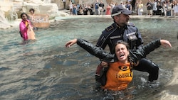 Klimaaktivisten der Letzten Generation werden von der italienischen Polizei abgeführt, nachdem sie am Trevi-Brunnen in Rom ein Transparent gegen die Nutzung fossiler Brennstoffe gezeigt haben. (Bild: AP)