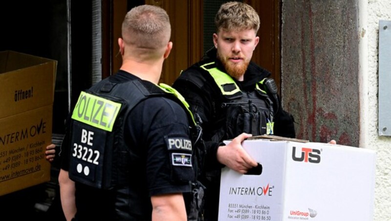 Kartonweise trugen die Polizisten Beweismittel aus den durchsuchten Gebäuden heraus. (Bild: APA/AFP/John MACDOUGALL)