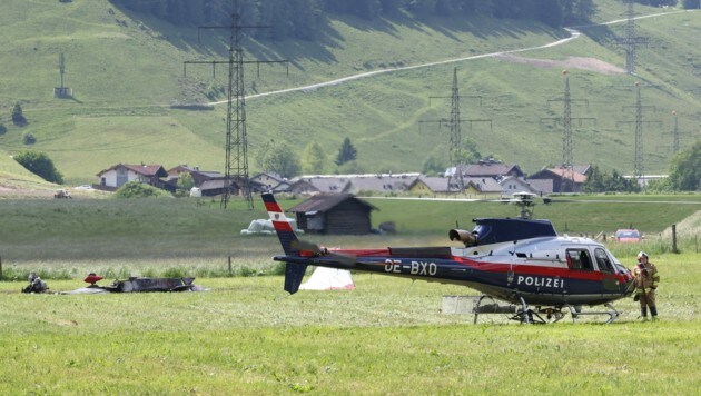 Das schwer demolierte Flugzeugwrack (links) neben dem Polizei-Hubschrauber auf einer Wiese in Bruck an der Großglocknerstraße (Bild: Roland Hoelzl)