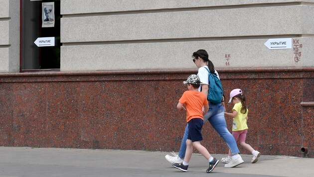 Eine Frau geht mit ihren Kindern an einem Schild mit der Aufschrift „Schutzbunker“ in der russischen Stadt Belgorod vorbei. (Bild: AFP)