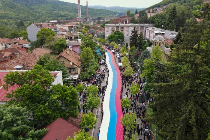 Menschen halten eine riesige serbische Flagge in der Stadt Zvecan.