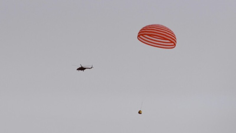 Hier landet die Raumkapsel an einem großen rot-weißen Fallschirm. (Bild: APA/AFP/STR)