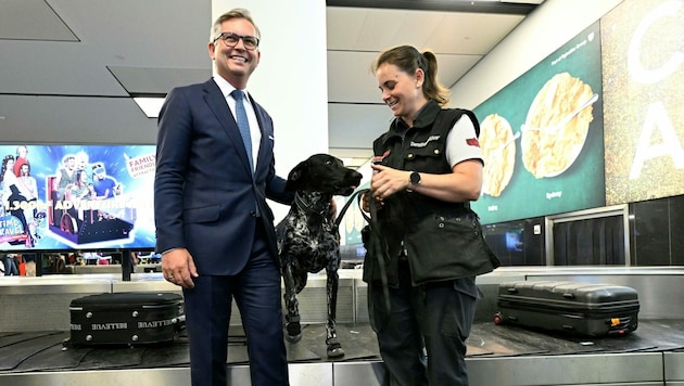 Finanzminister Magnus Brunner (ÖVP) und eine Diensthundeführerin am Montag auf der Pressekonferenz „Zolljahresbilanz Flughafen Wien 2022“ am Flughafen Wien. (Bild: APA/HELMUT FOHRINGER)