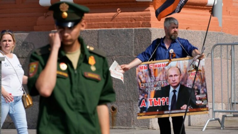 Ein Aktivist hält am Sonntag in der Nähe des Kremls in Moskau, Russland, ein Plakat mit einem Bild des russischen Präsidenten Wladimir Putin auf dem steht: „Wir sind an deiner Seite und für die Souveränität Russlands.“ (Bild: ASSOCIATED PRESS)