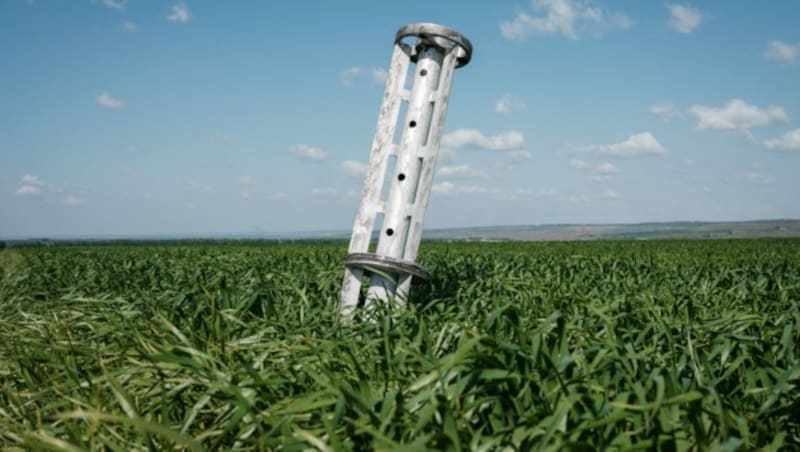 Das Fragment einer Streubombe steckt in einem Feld in der Ostukraine. (Bild: APA/AFP/Yasuyoshi Chiba)