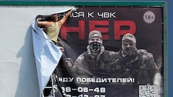 Ein Werbeplakat für die Wagner-Gruppe wird in St.Petersburg entfernt. (Bild: AP)