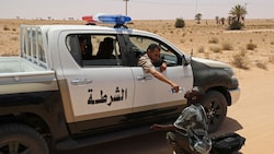 Ein Grenzpolizist gibt einem Migranten in der tunesischen Wüste Wasser zu trinken. (Bild: AFP)