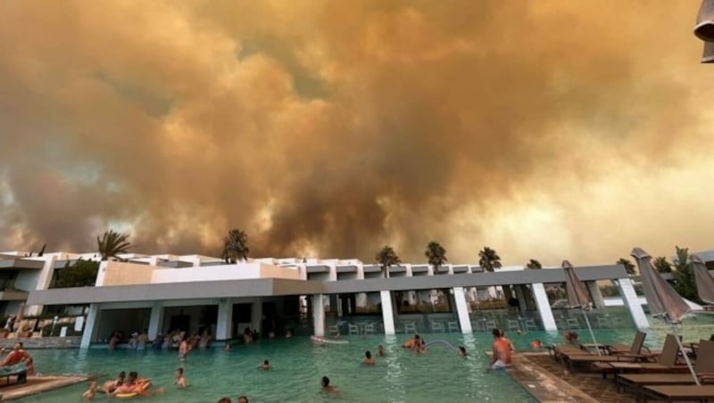 Während im Hintergrund die Rauchwolken zu sehen waren, badeten die Menschen am Samstagnachmittag noch im Hotelpool. (Bild: zVg)