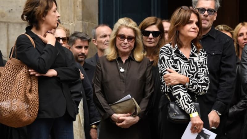 Nach der Zeremonie verlassen auch die französische Schauspielerin Catherine Deneuve (Mitte), gefolgt von Tochter Chiara Mastroianni und dem französischen Künstler Benjamin Biolay die Kirche. (Bild: APA/AFP/JULIEN DE ROSA)