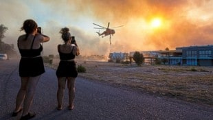 Löschhelikopter kreisen rund um die Uhr. Touristen fotografieren. Es ist ein Kampf auf Biegen und Brechen, um letzte Habseligkeiten zu retten. (Bild: Reuters/Nicolas Economou)