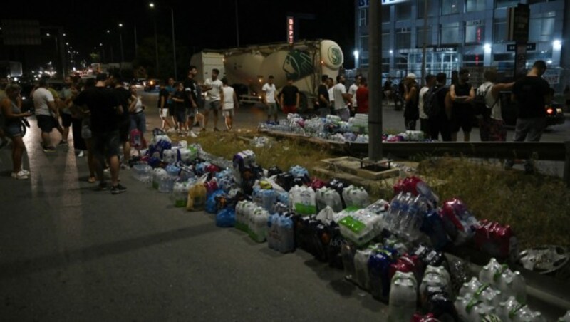 Menschen in Volos bringen Wasserflaschen zu den Feuerwehrleuten. (Bild: AFP)