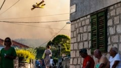 Ein Flugzeug versprüht Wasser, um den Waldbrand auf der Insel Ciovo zu löschen. (Bild: The Associated Press)