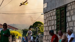 Ein Flugzeug versprüht Wasser, um den Waldbrand auf der Insel Ciovo zu löschen. (Bild: The Associated Press)