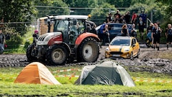 Ein Traktor zieht ein Auto auf dem Festivalgelände aus dem Schlamm. (Bild: AFP)