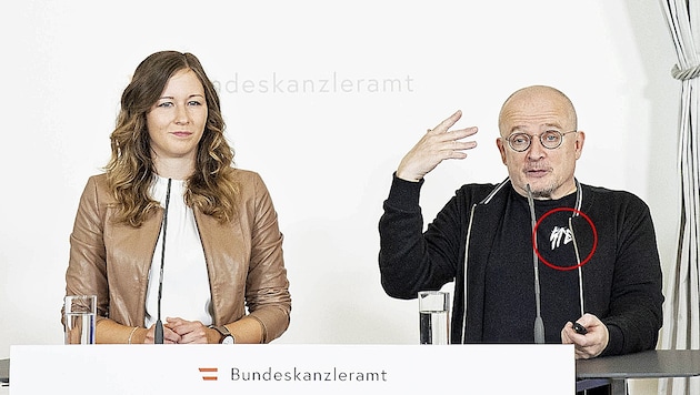 Die Zeichen auf dem T-Shirt von Jugendforscher Bernhard Heinzlmaier bei der Pressekonferenz mit Jugendstaatssekretärin Claudia Plakolm (ÖVP) sorgten für Wirbel. (Bild: APA/TOBIAS STEINMAURER)