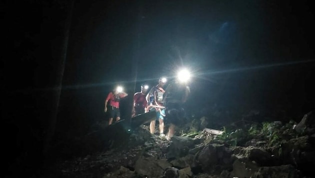 Die Helfer bringen das Paar, das ohne Lampe unterwegs war, von der Dachenwand (Bild: Bergrettung Mondseeland)