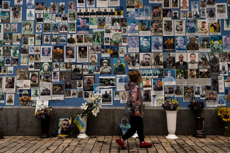 Ein kleines Mädchen betrachtet an der Mauer der Erinnerung in Kiew Fotos ukrainischer Soldaten, die im Krieg getötet wurden. (Bild: AP)