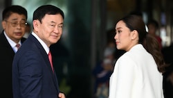Der frühere Regierungschef Thaksin Shinawatra mit seiner Tochter bei der Ankunft am Flughafen (Bild: AFP)