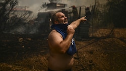 Ein Mann aus dem Athener Außenbezirk Chasia ist verzweifelt. Die griechische Feuerwehr ordnete die Evakuierung an, während die Feuerwehr gegen eine stetig wachsende Welle von Waldbränden im ganzen Land kämpfte. (Bild: AFP)