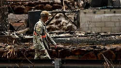 Ein Mitglied der US-Nationalgarde schreitet durch vollkommen niedergebrannte Viertel. (Bild: APA/AFP/Patrick T. Fallon)