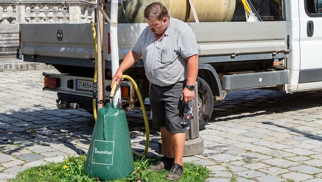 Gemeindemitarbeiter Christian Rößl füllt den Wasserspeicher des Baumes, der 75 Liter fasst. (Bild: Klaus Schindler)