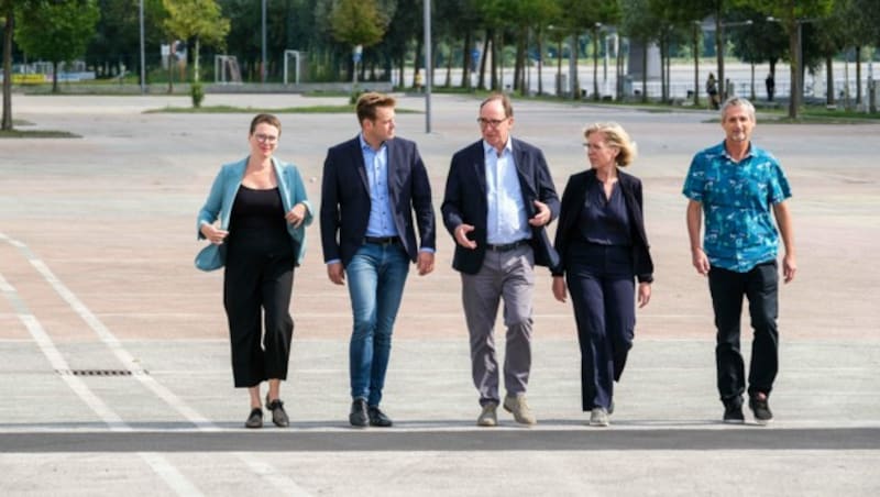 Klimastadträtin Eva Schobesberger, Umwelt- und Klima-Landesrat Stefan Kaineder, Sozial- und Gesundheitsminister Johannes Rauch, Klimaschutzministerin Leonore Gewessler, Umweltmediziner Hans-Peter Hutter gehen über eine der vielen versiegten Flächen in Linz, die in Zukunft bepflanzt werden sollen. (Bild: Horst Einöder/Flashpictures)