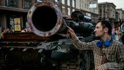 Ein Ukrainer inspiziert einen zerstörten russischen Kampfpanzer. (Bild: AFP or licensors)