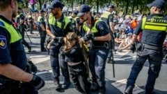 Polizisten entfernen einen Klimaaktivisten der Gruppe Extinction Rebellion (Bild: AFP)