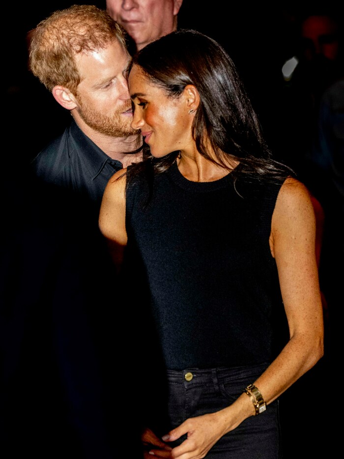 Prinz Harry flüstert Meghan etwas ins Ohr.
