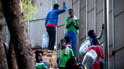 Diese Männer versuchen aus dem überfüllten Aufnahmezentrum zu entkommen. (Bild: APA/AFP/Alessandro Serranò)