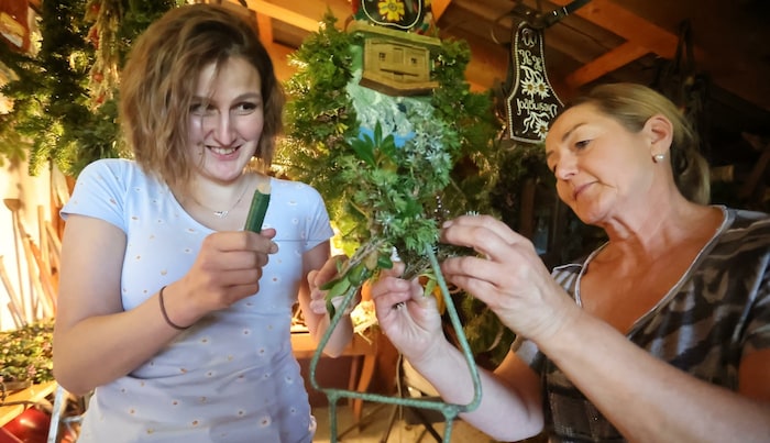 Christine Knapp zeigt Redakteurin Nicole Greiderer, wie das Almbuschenbinden funktioniert.