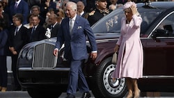 König Charles und Königin Camilla, deren Hut wegzufliegen droht, in Paris. (Bild: APA/AFP/POOL/Yoan VALAT)