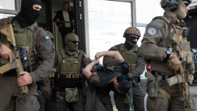 Kosovarische Polizisten eskortieren einen der bewaffneten Männer nach der Schießerei am vergangenen Dienstag. (Bild: ASSOCIATED PRESS)
