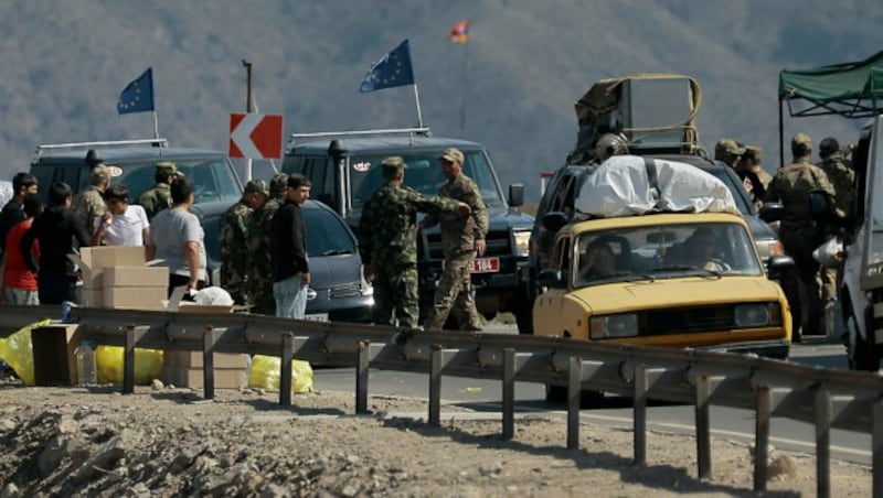 Flüchtlinge und EU-Beobachter bei einem militärischen Checkpoint in Bergkarabach (Bild: AP)