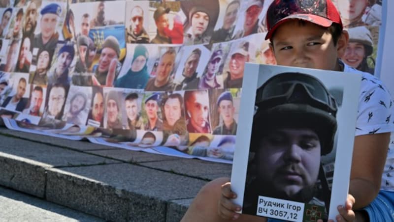 Ein Kind mit einem Porträt seines Bruders während einer Kundgebung von Angehörigen vermisster und inhaftierter ukrainischer Soldaten. (August 2023) (Bild: AFP)