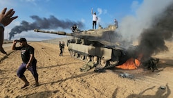Palästinenser feiern einen zerstörten israelischen Panzer. (Bild: ASSOCIATED PRESS)