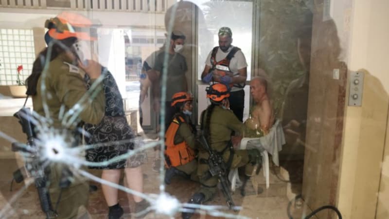 Israelische Rettungsteams kümmern sich um einen älteren Mann. Das Gebäude, in dem er sich aufhält, war direkt von einer Rakete aus dem Gazastreifen getroffen worden. (Bild: APA/AFP/AHMAD GHARABLI)
