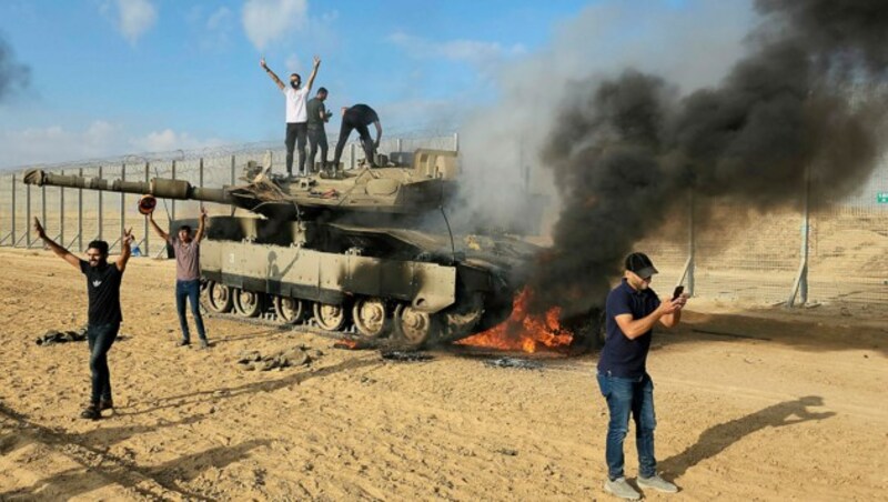 Palästinenser bejubeln die Zerstörung eines israelischen Panzers an der Grenze. (Bild: AP)