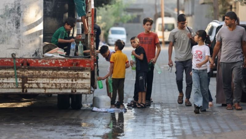 Palästinensische Buben füllen in Rafah Flaschen mit Wasser aus einer mobilen Zisterne. (Bild: APA/AFP/MOHAMMED ABED)