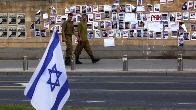 Israelische Soldaten gehen an Bildern israelischer Geiseln vorbei, die von der palästinensischen militanten Gruppe Hamas bei dem Überraschungsangriff auf Israel entführt wurden. (Bild: APA/AFP/AHMAD GHARABLI)