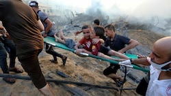 Zwei verletzte Buben im Gazastreifen werden nach israelischen Luftangriffen in Sicherheit gebracht. (Bild: Associated Press)