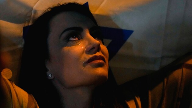 Eine Frau weint unter einer Israel-Flagge.  (Bild: AP, Krone KREATIV)