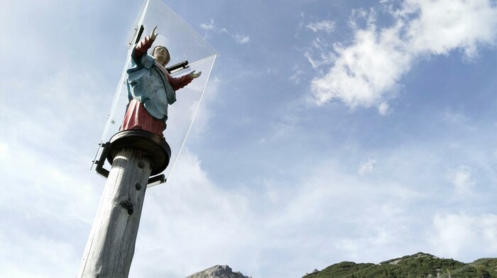 Eine Marienstatue thront auf einer über vier Meter hohen Lärchensäule direkt neben der Alm.