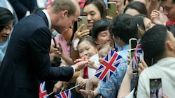 Das Baby ist komplett angetan von Prinz Williams Finger. (Bild: APA/AP Photo/Vincent Thian)