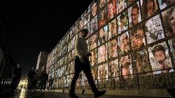 Ein Mann am 6. November 2023 vor den Mauern der Altstadt von Jerusalem. Auf die Mauer projiziert: Bilder der Geiseln, die von Palästinensern entführt wurden und im Gazastreifen festgehalten werden. (Bild: AFP/AHMAD GHARABLI)