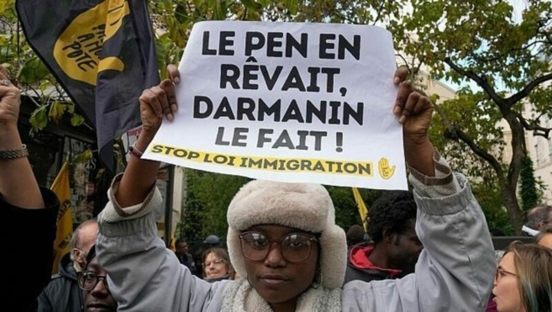 In Frankreich ist ein verschärftes Einwanderungsgesetz geplant. Dagegen wird gerade protestiert, diese Person hält ein Schild mit der Aufschrift „Le Pen hat davon geträumt, Darmanin hat es gemacht.“ (Bild: glomex)