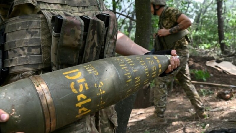 Ein ukrainischer Artillerist trägt eine 155-mm-Granate und feuert mit einer Haubitze M777 auf russische Stellungen in der Nähe von Awdijiwka in der Region Donezk. (Bild: AFP)