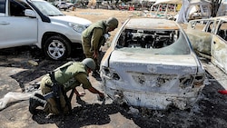 Forensiker der israelischen Armee bei ausgebrannten Wracks am Festivalgelände (Bild: APA/AFP/JACK GUEZ)